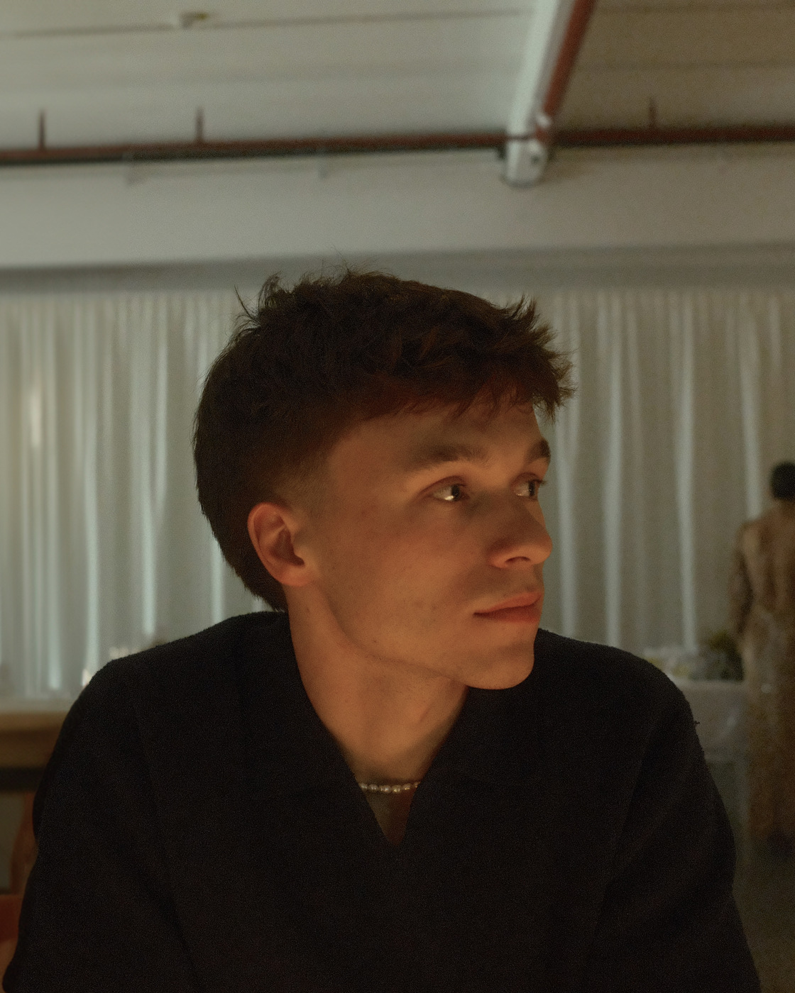 Portrait of Tim Sledz in a dark shirt, looking off to the side in warm low light.